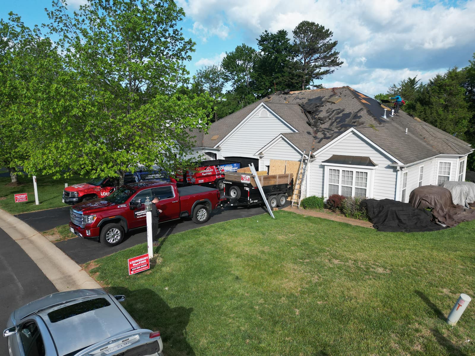 Lounsbury Roofing crew on-site with branded trucks during a tear-off