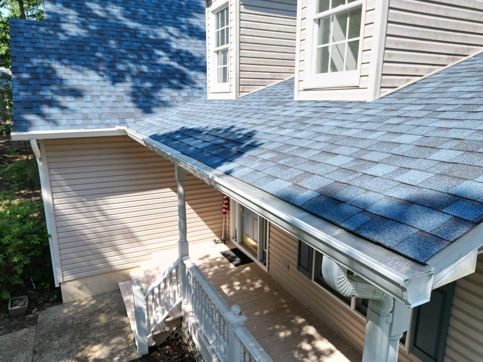 Close-up of a Lounsbury Roofing eave install — new architectural shingles meeting clean 6-inch gutter line